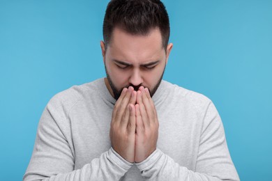 Photo of Sick man coughing on light blue background