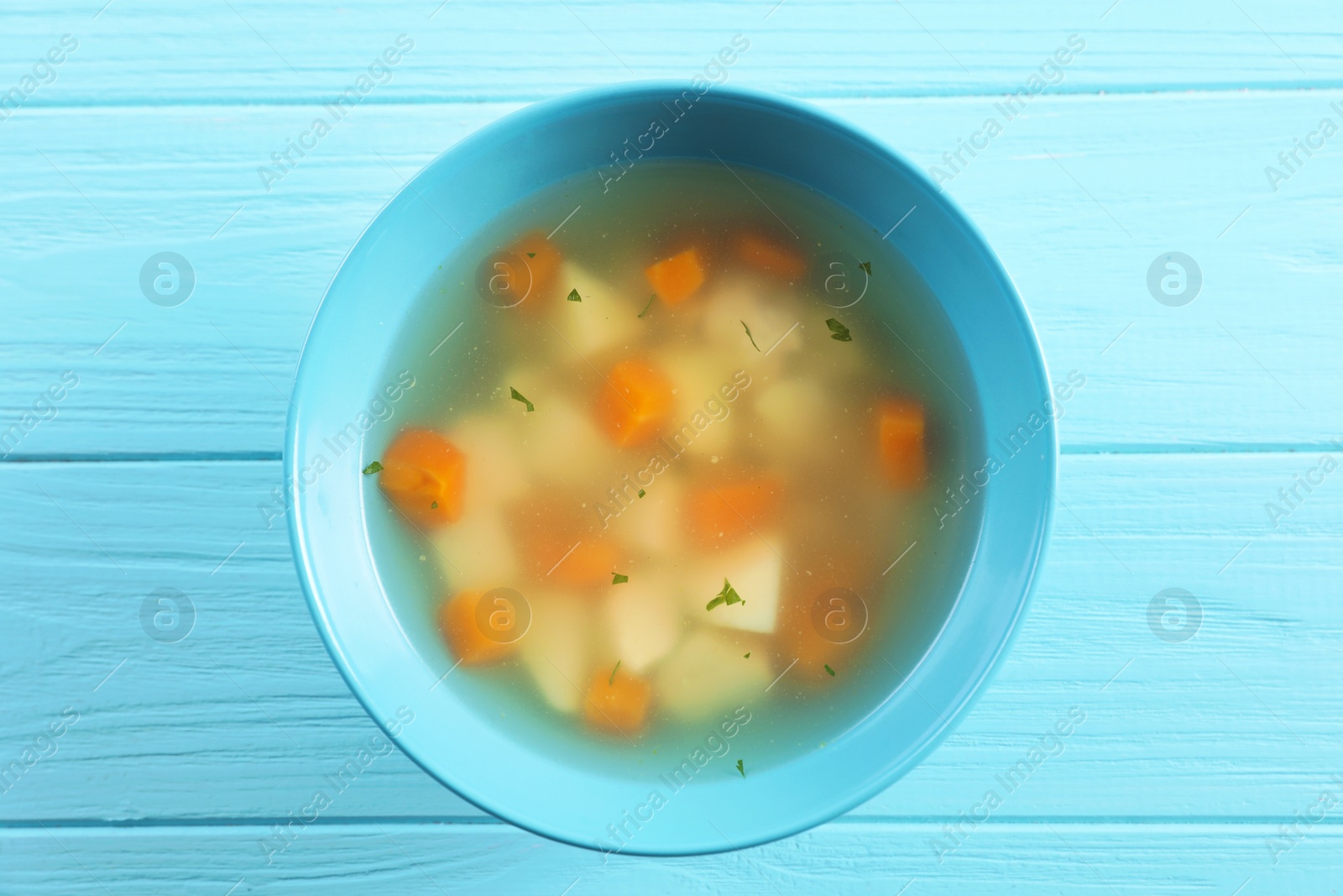 Photo of Bowl of fresh homemade soup to cure flu on wooden background, top view