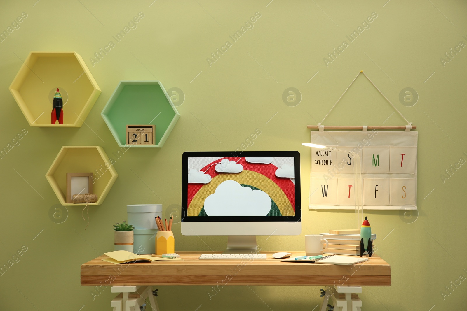 Photo of Stylish workplace with computer on wooden desk near light green wall. Interior design