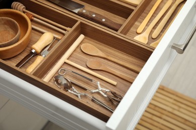 Photo of Open drawer of kitchen cabinet with different utensils, closeup