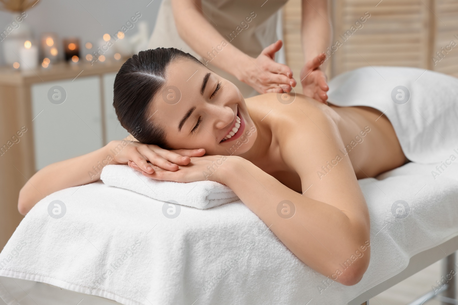 Photo of Woman receiving back massage on couch in spa salon