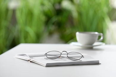 Stylish glasses and notebook on white table indoors