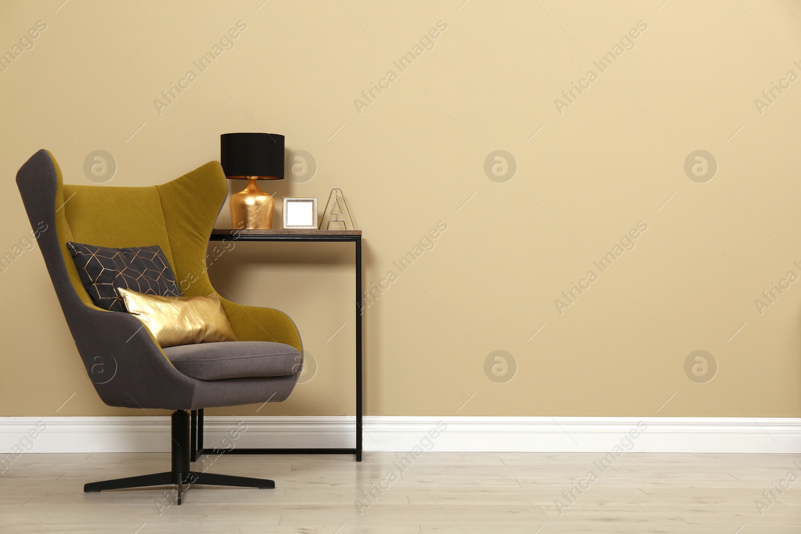 Photo of Armchair and console table near beige wall in room, space for text. Interior design
