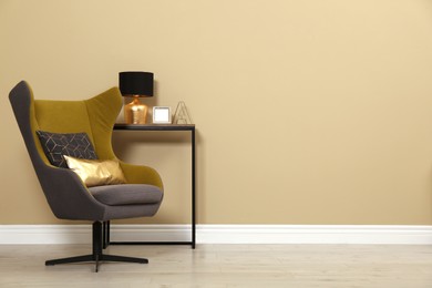 Photo of Armchair and console table near beige wall in room, space for text. Interior design