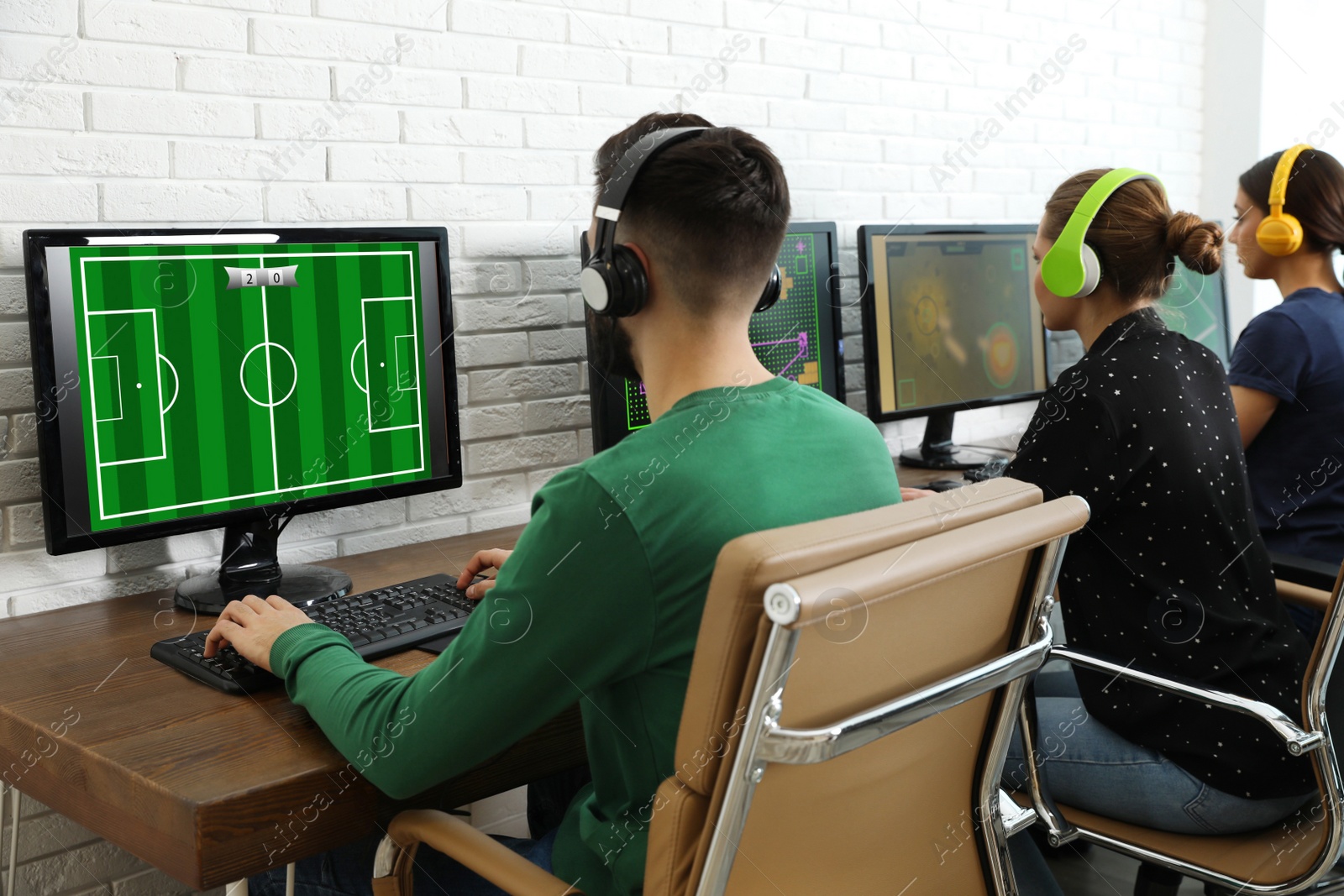 Photo of Young people playing video games on computers indoors. Esports tournament