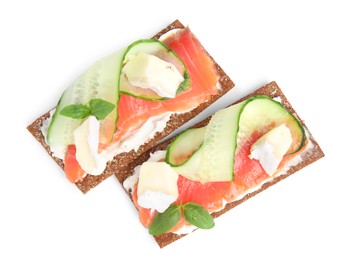 Tasty rye crispbreads with salmon, cream cheese and cucumber isolated on white, top view