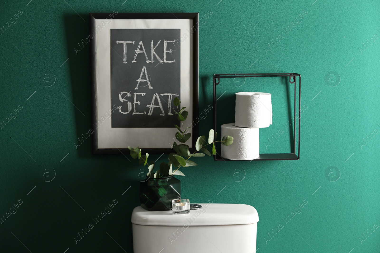 Photo of Decor elements, paper rolls and toilet bowl near green wall. Bathroom interior