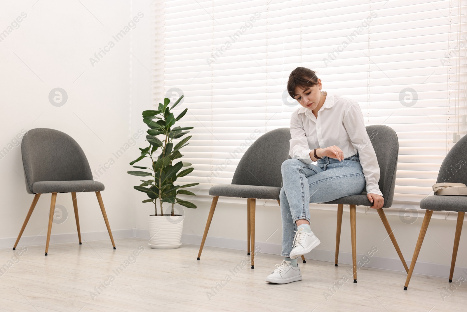 Photo of Woman sitting on chair and waiting for appointment indoors