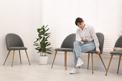 Woman sitting on chair and waiting for appointment indoors