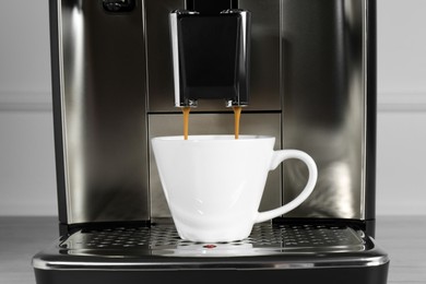 Photo of Espresso machine pouring coffee into cup on drip tray, closeup