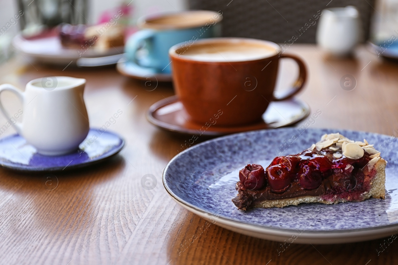 Photo of Plate with slice of cherry cake on wooden table