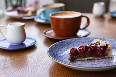 Plate with slice of cherry cake on wooden table