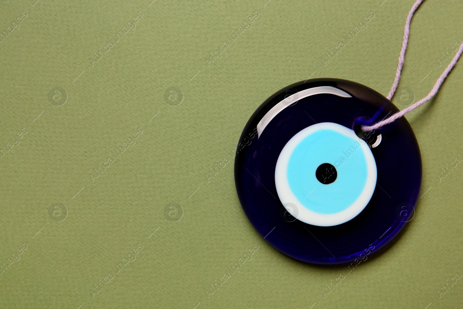 Photo of Evil eye amulet on olive background, top view. Space for text