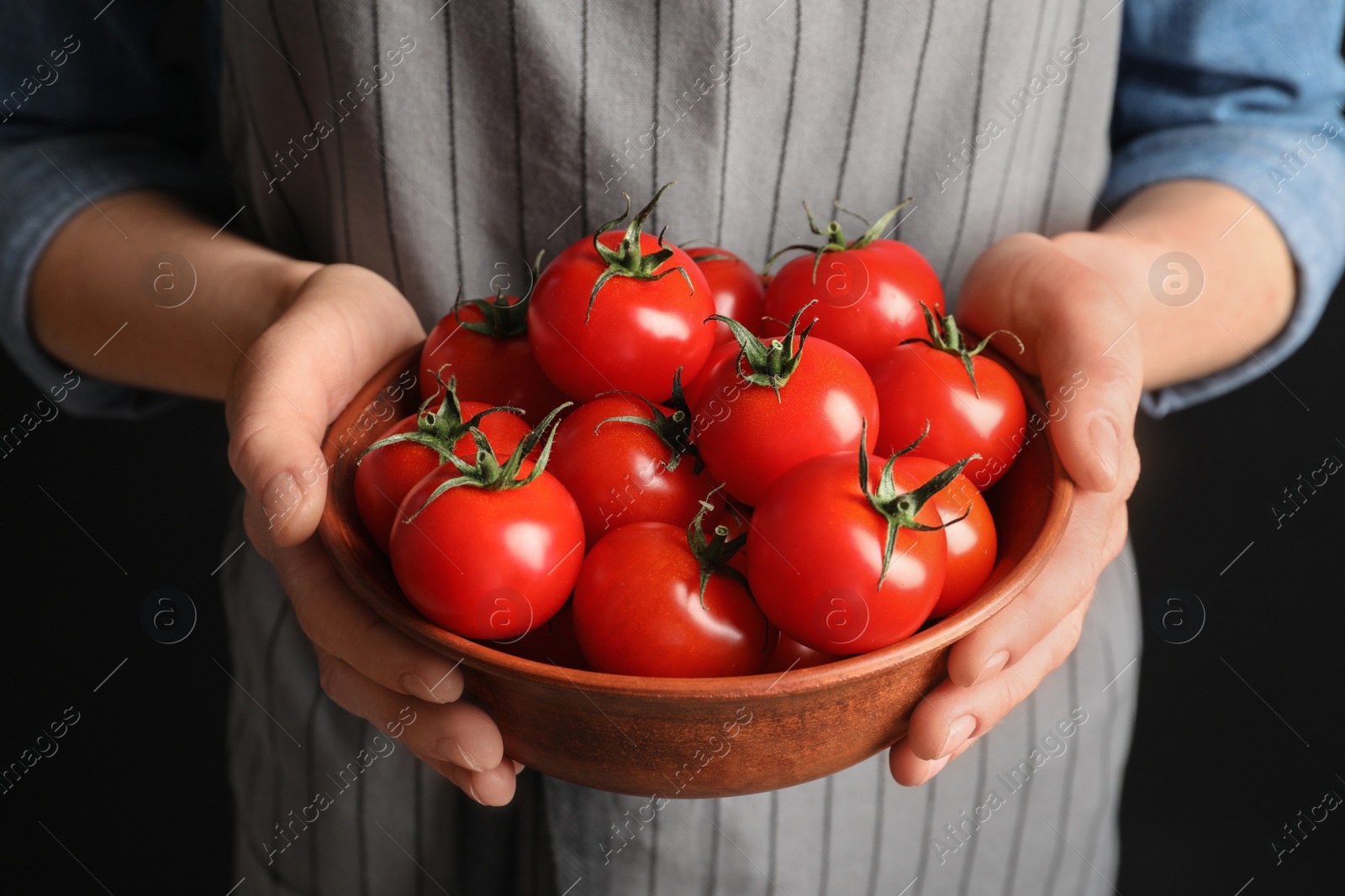 Photo of Woman holding wooden bowl with ripe cherry tomatoes, closeup