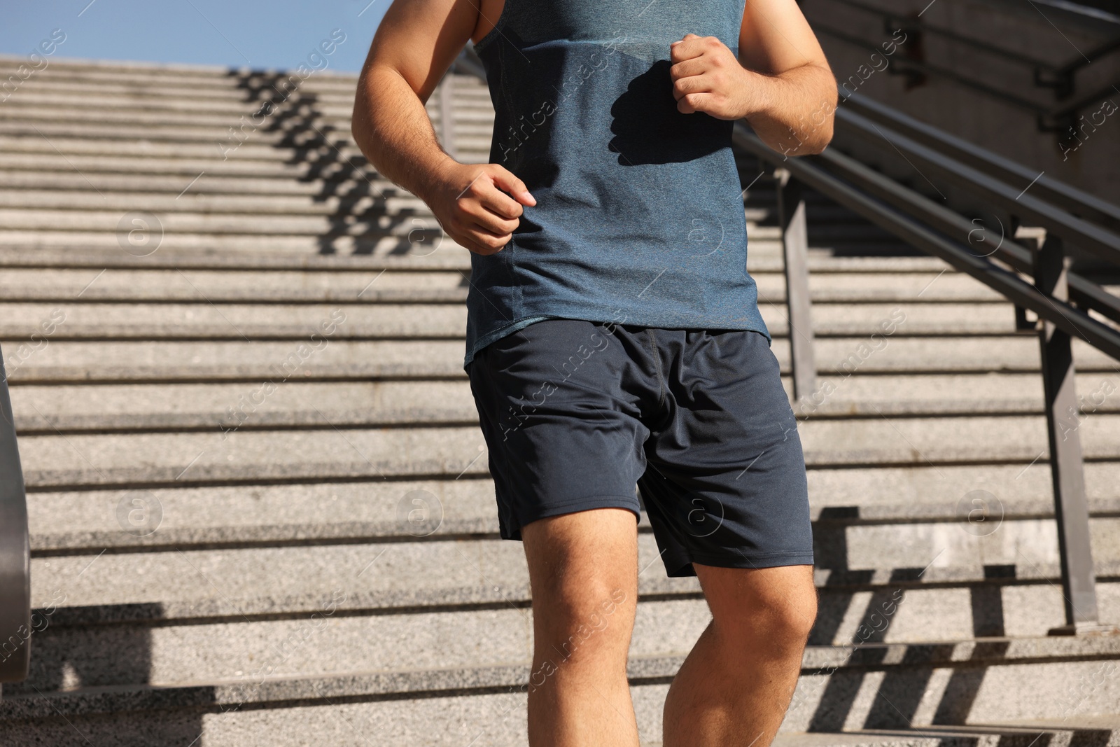 Photo of Man running down stairs outdoors on sunny day, closeup