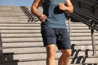 Photo of Man running down stairs outdoors on sunny day, closeup