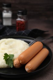 Delicious boiled sausages, mashed potato and parsley on table, closeup