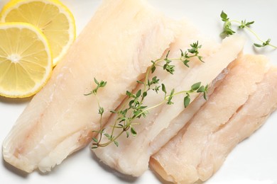 Photo of Pieces of raw cod fish and lemon on plate, closeup