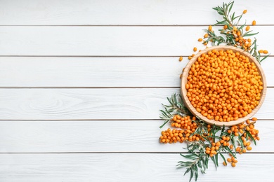 Photo of Fresh ripe sea buckthorn on white wooden table, flat lay. Space for text