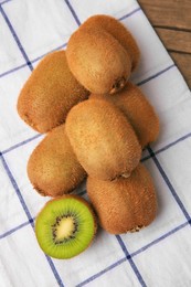 Photo of Heap of whole and cut fresh kiwis on wooden table, top view