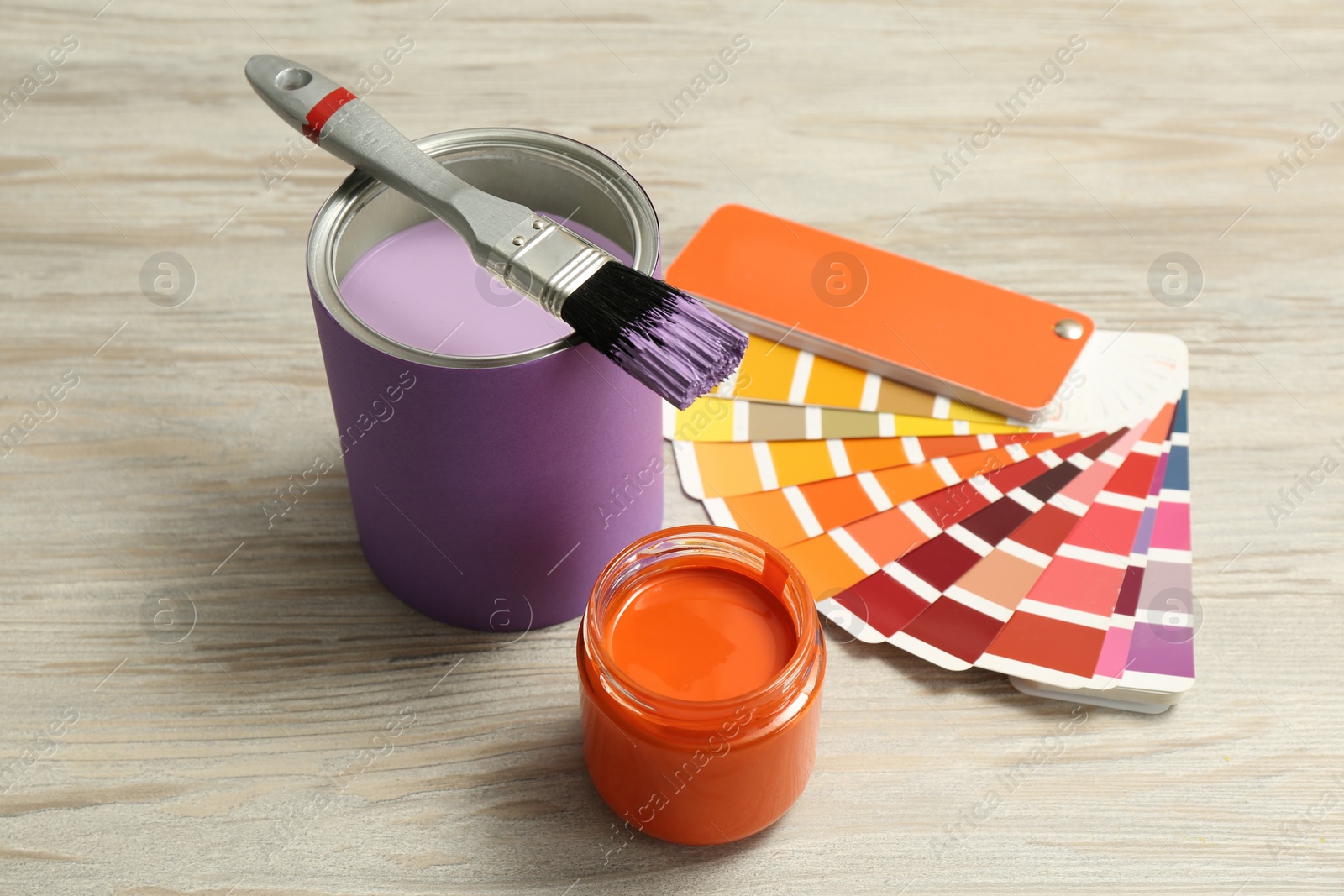 Photo of Different paints with brush and palette on light wooden background