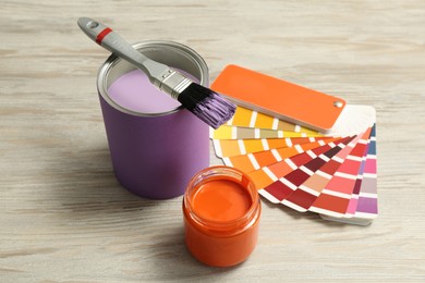 Photo of Different paints with brush and palette on light wooden background