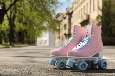 Photo of Stylish pink roller skates outdoors on sunny day. Space for text