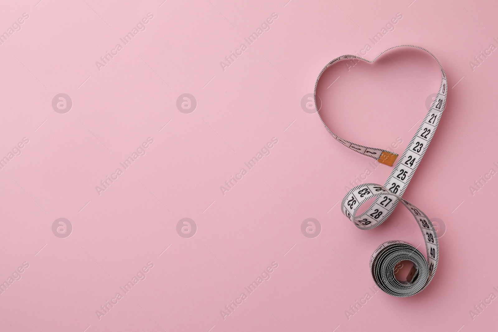 Photo of Measuring tape on pink background, top view. Space for text