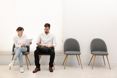 Man and woman waiting for job interview indoors