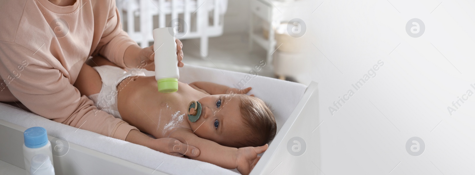 Image of Mother applying dusting powder on her cute baby at home. Banner design