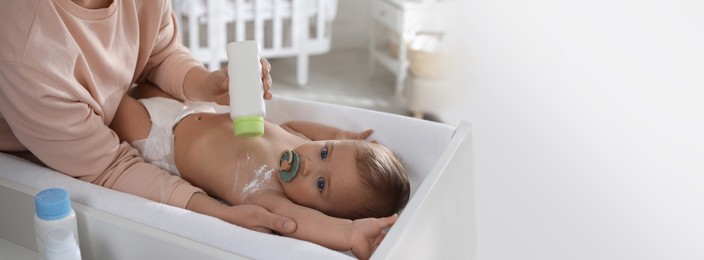 Mother applying dusting powder on her cute baby at home. Banner design