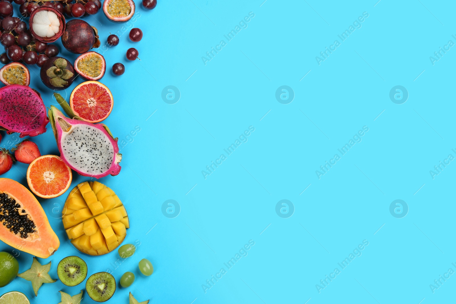 Photo of Many different delicious exotic fruits on light blue background, flat lay. Space for text