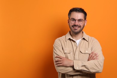 Portrait of happy man in stylish glasses on orange background, space for text