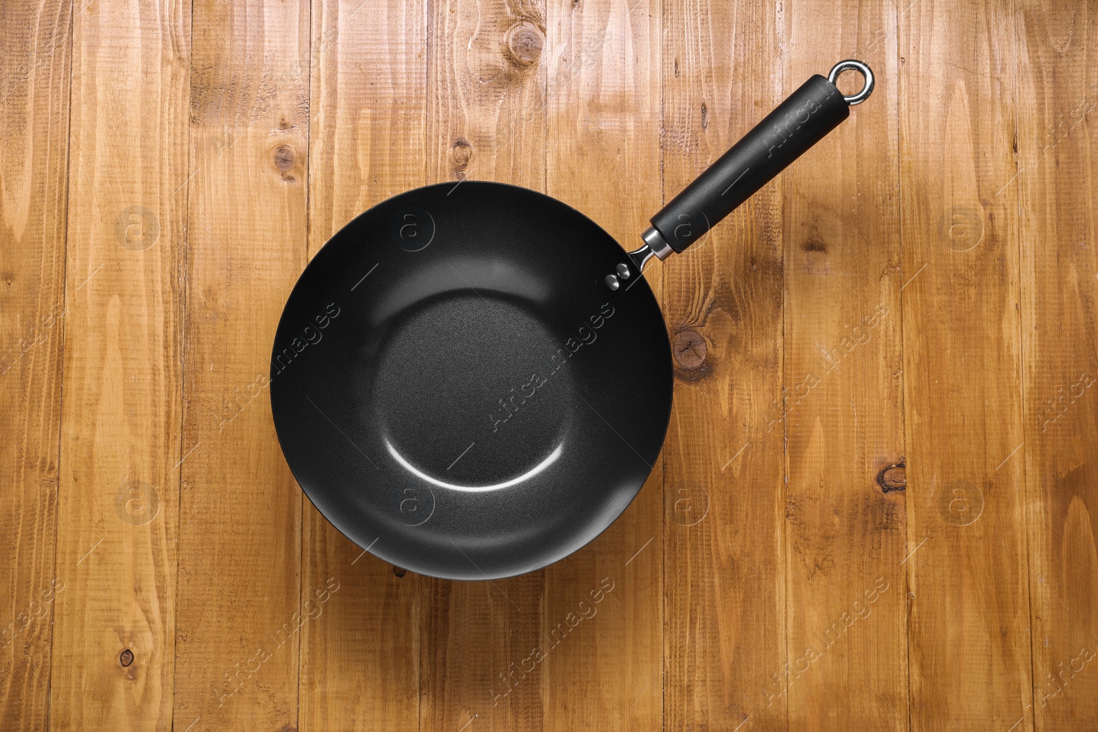 Photo of Empty iron wok on wooden table top view. Chinese cookware