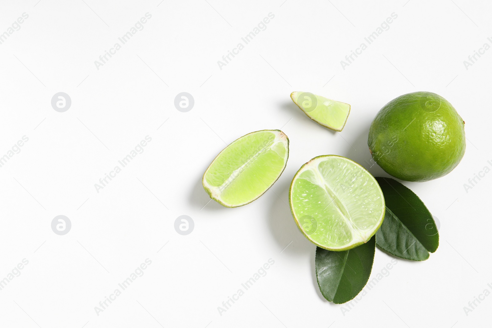 Photo of Fresh ripe limes and leaves on white background, flat lay. Space for text