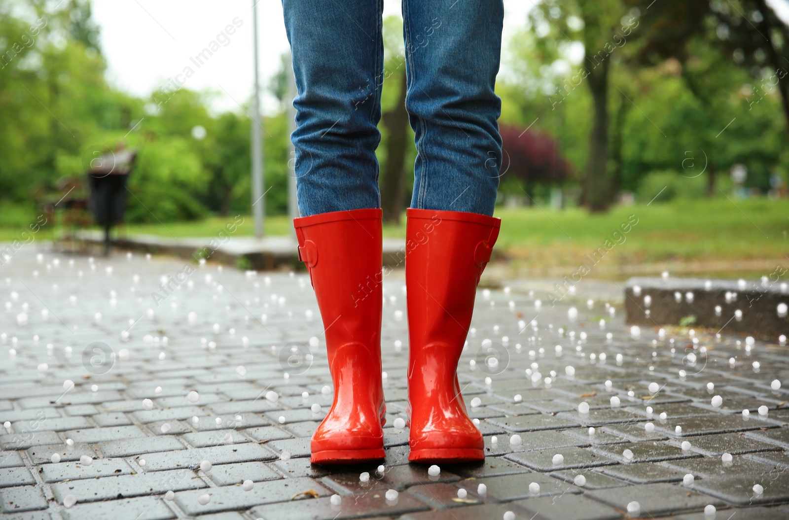 Image of Woman wearing red rubber boots outdoors after thunderstorm with hail, closeup 