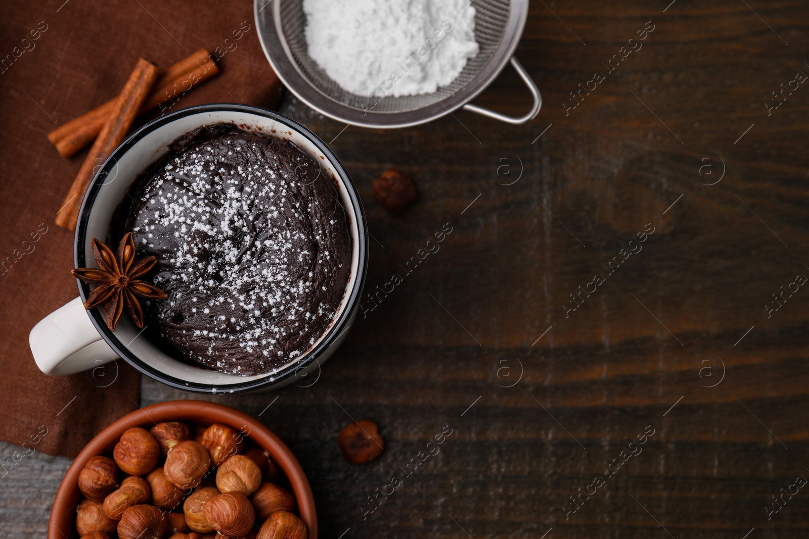 Photo of Tasty chocolate mug pie and ingredients on wooden table, flat lay with space for text. Microwave cake recipe