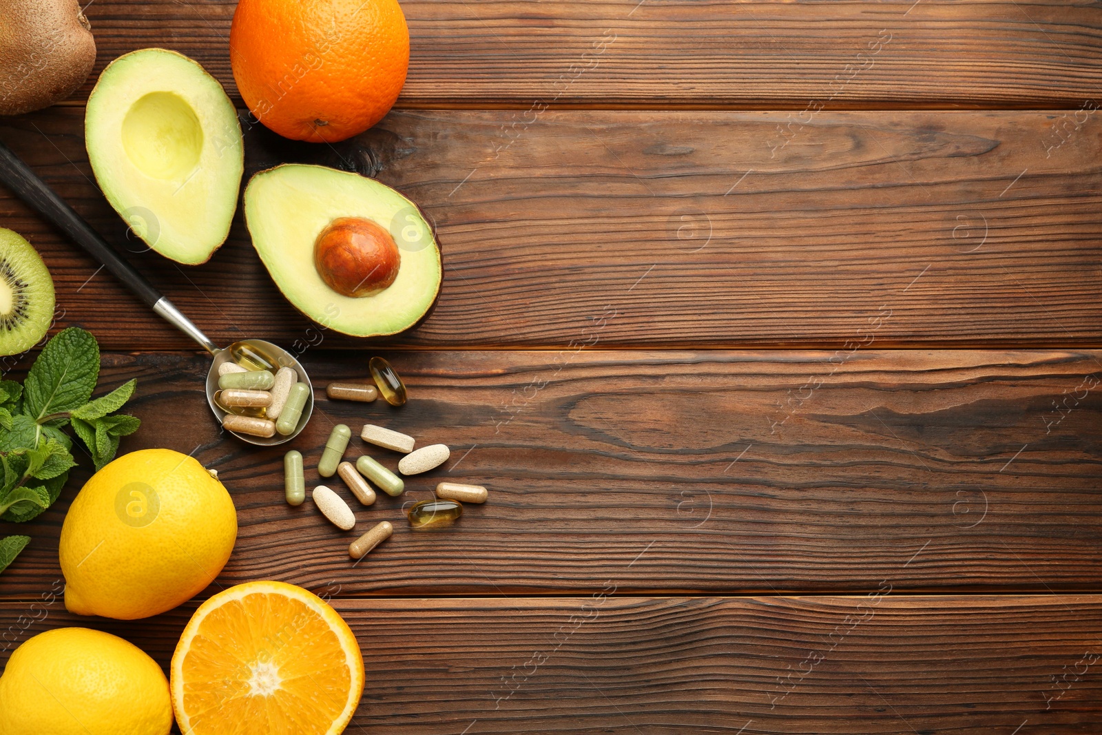 Photo of Different vitamin pills and fresh fruits on wooden table, flat lay. Space for text