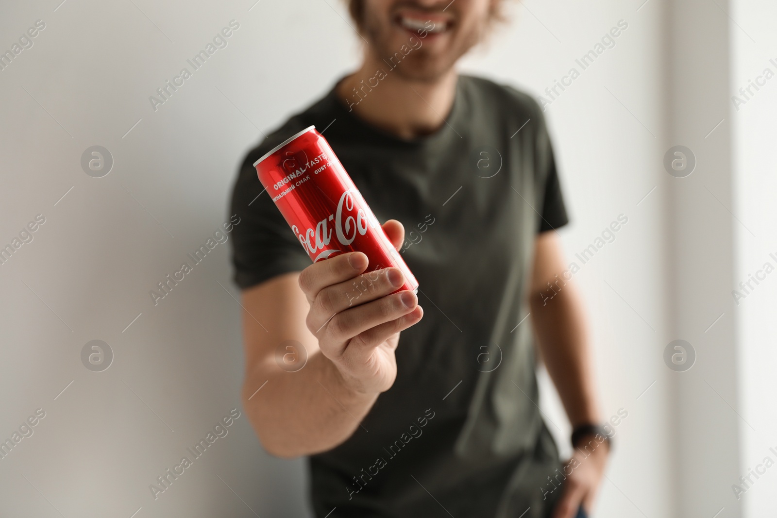 Photo of MYKOLAIV, UKRAINE - NOVEMBER 28, 2018: Young man with Coca-Cola can indoors, closeup