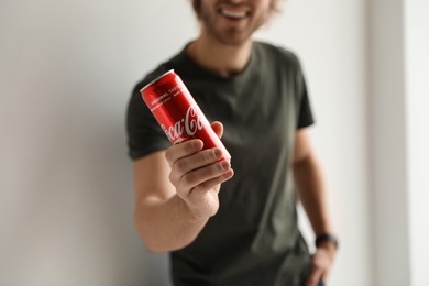 MYKOLAIV, UKRAINE - NOVEMBER 28, 2018: Young man with Coca-Cola can indoors, closeup