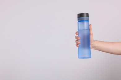 Photo of Man holding transparent plastic bottle with drink on light grey background, closeup. Space for text