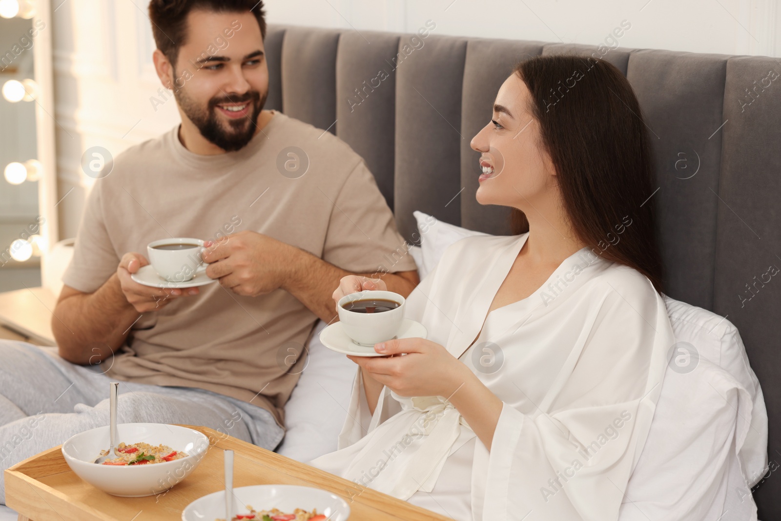 Photo of Happy couple having breakfast on bed at home