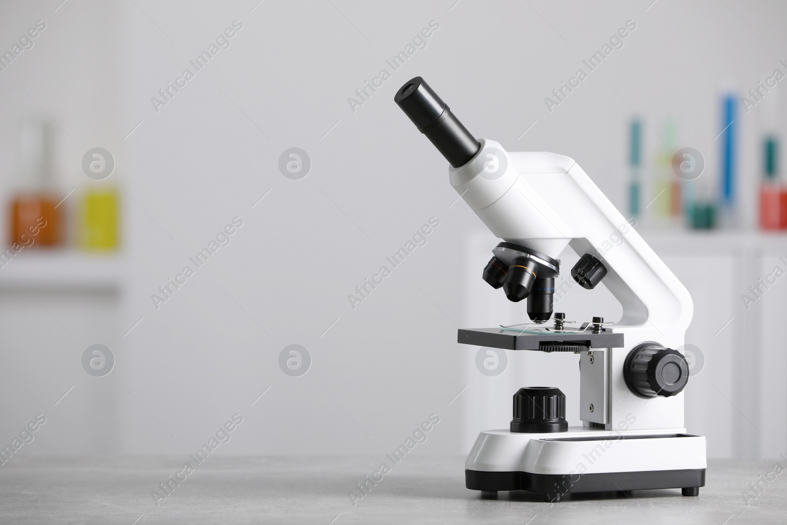 Photo of Modern medical microscope on grey table in laboratory, space for text