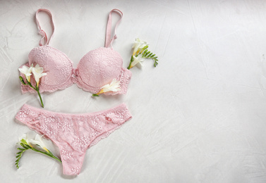 Photo of Sexy women's underwear and flowers on light background, flat lay. Space for text