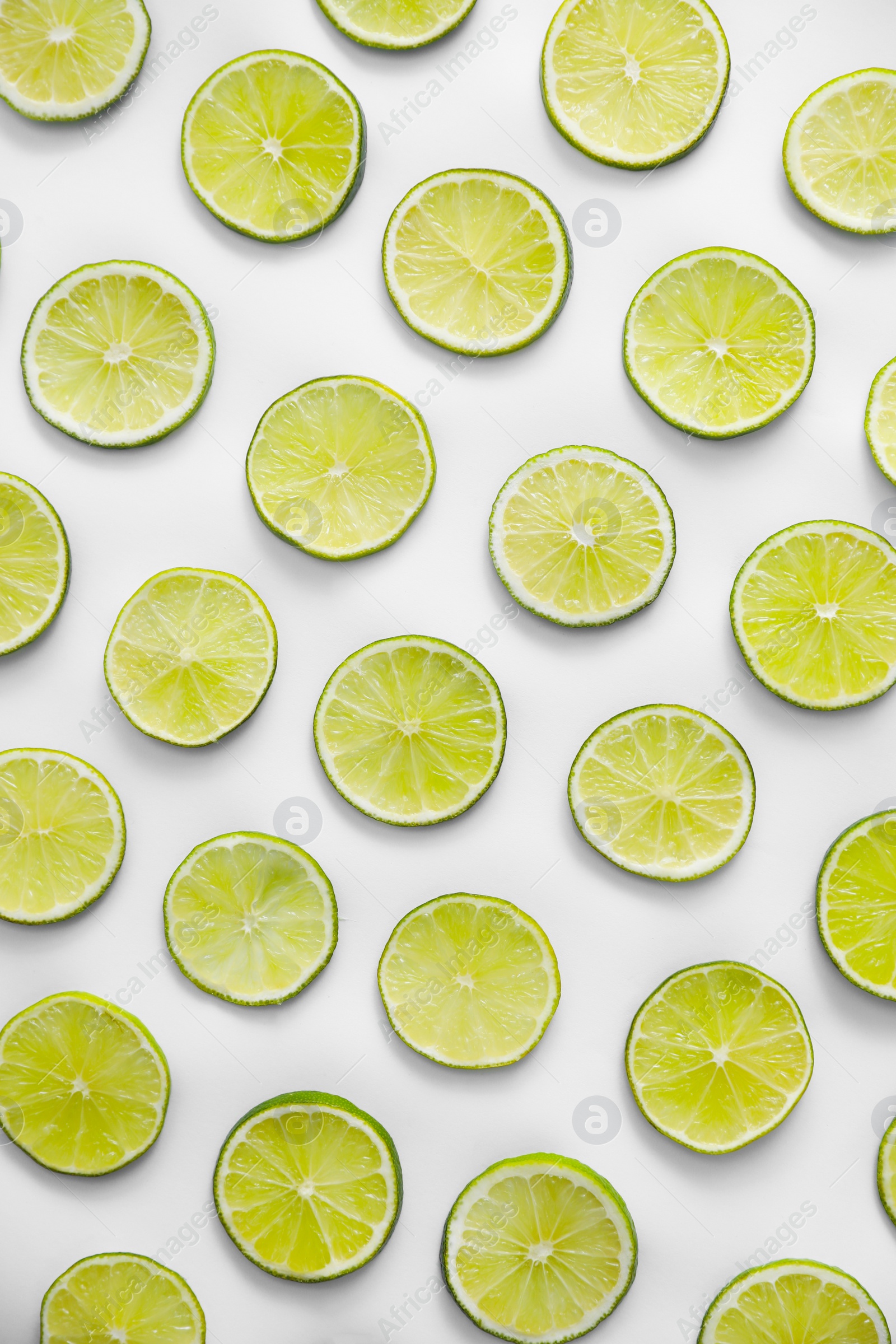 Photo of Slices of fresh juicy limes on white background, flat lay