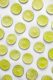 Photo of Slices of fresh juicy limes on white background, flat lay