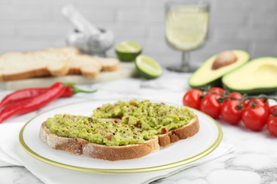 Photo of Delicious sandwiches with guacamole and ingredients on white table