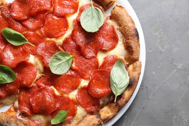 Tasty pepperoni pizza with basil on grey table, top view