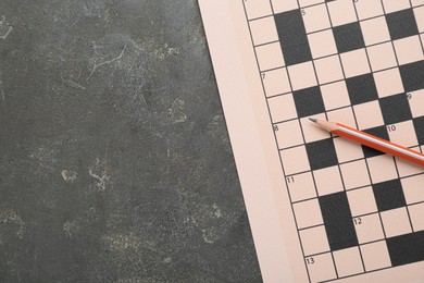 Photo of Blank crossword and pencil on grey table, top view. Space for text