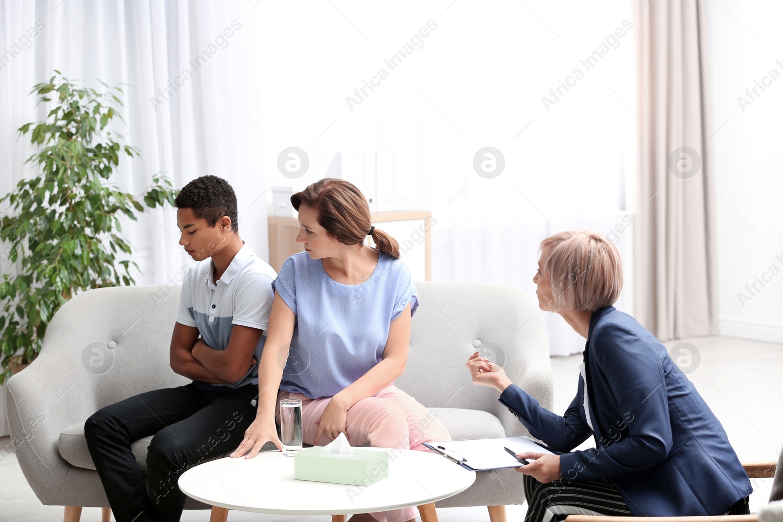 Photo of Psychotherapist working with African-American teenage boy and his mother in office